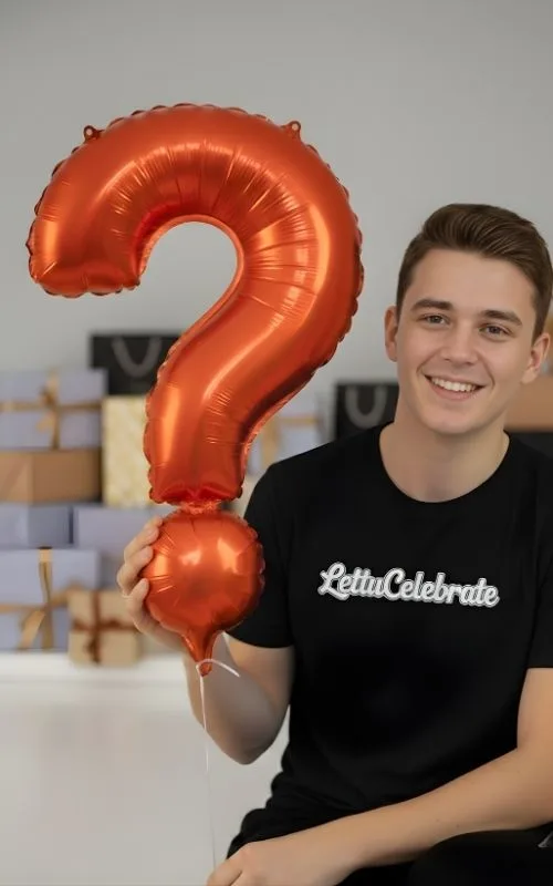 A man in a black t-shirt holding a large orange question mark balloon.